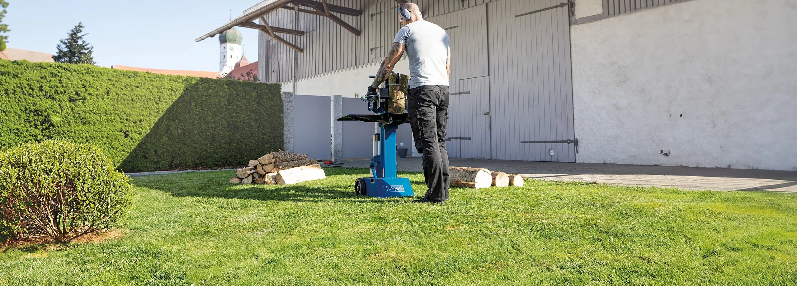 Mann betätigt einen Scheppach Holzspalter im Garten