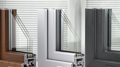 Tres secciones de marco de ventana (marrón, blanco, gris) mostrando triple acristalamiento y estructura interna.