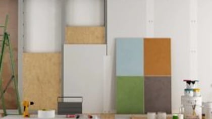 Escena de renovación con escalera verde, materiales de construcción, botes de pintura y muestras de color en el suelo.