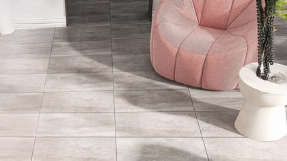 Heller Raum mit quadratischen Bodenfliesen in Holzoptik, einem rosa Sessel und einem weißen Beistelltisch mit Pflanze.