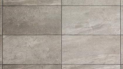 Azulejos rectangulares grises con texturas de piedra variadas y vetas sutiles, creando una superficie modular.