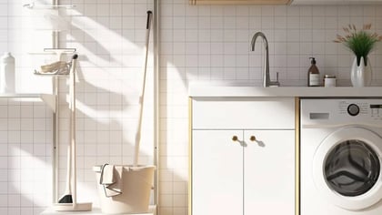 Lavadero moderno con lavadora blanca, fregadero y armarios, productos de limpieza y una planta.