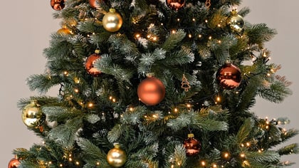 Geschmückter Weihnachtsbaum mit goldenen und bronzefarbenen Kugeln sowie warmen Lichtern für festliche Stimmung.