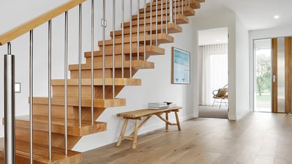 Escalera moderna de madera con balaustres de acero inoxidable y pasamanos en un hogar contemporáneo.