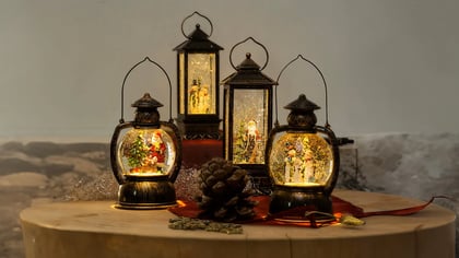 Festliche Szene mit einer Kollektion beleuchteter Weihnachtswasserlaternen auf einem Holztisch, die eine warme, weihnachtliche Atmosphäre erzeugen.