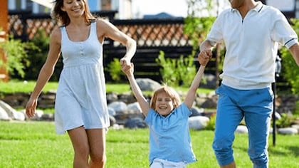 Una familia feliz columpia a su hijo de las manos al aire libre.