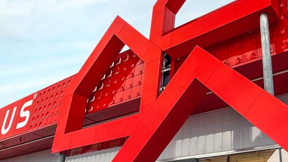 Llamativo edificio Bauhaus rojo con elementos arquitectónicos angulares en forma de estrella y logo visible.