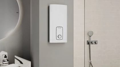 Nahaufnahme eines modernen Badezimmers mit einem eleganten runden Spiegel, einem weißen Warmwasserbereiter und einer stilvollen Dusche.