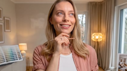 Mujer sonriente con un lápiz, planificando la decoración del hogar con un libro de muestras de color.