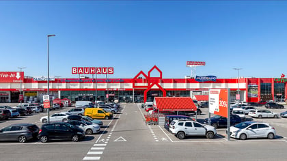 Gran tienda Bauhaus de bricolaje con fachada roja y blanca, señalización destacada y un aparcamiento concurrido bajo cielo azul.
