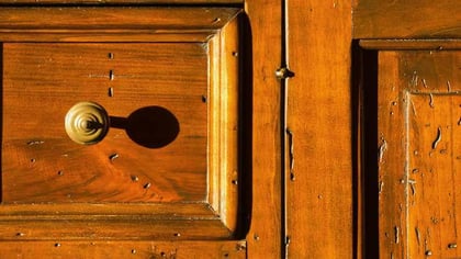 Tirador de latón pulido en un panel de puerta de madera rústica color miel.