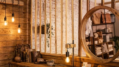 Rustikales Holzinterieur mit warmen Edison-Hängelampen und einem großen runden Holzspiegel, der eine gemütliche Atmosphäre schafft.