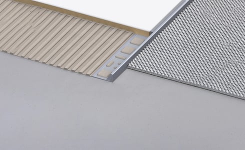 Aluminium-Übergangsprofil verbindet gerippte beige Unterlage mit silberner Strukturmatte.