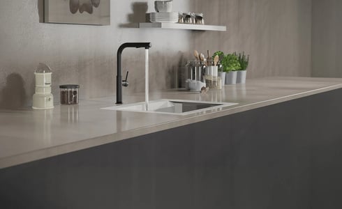 Schwarze Küchenarmatur über hellem integriertem Spülbecken, Wasser läuft, in moderner heller Arbeitsplatte.