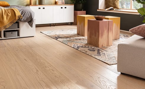 Heller Holzfußboden in einem gemütlichen Schlafzimmer mit Bett und Teppich. Breite Dielen schaffen eine helle, einladende Atmosphäre.