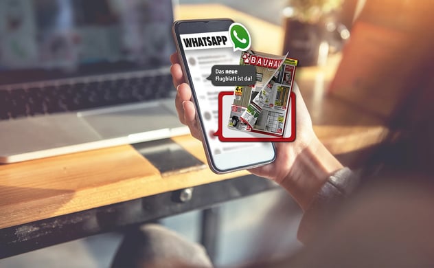Hand hält Smartphone mit WhatsApp-Nachricht, die einen Bauhaus-Flugblatt und den Text 'Das neue Flugblatt ist da!' zeigt.