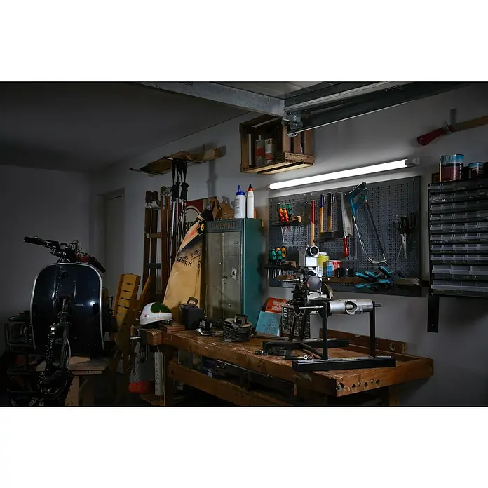 Osram LED-Lichtleiste Power Batten - L x B x H: 60 x 8,2 x 4,8 cm, Lichtfarbe: Warmweiß, 24 W, 220 V - 240 V - Eine Werkstatt mit einer Drehbank, Werkzeugen und einem Roller im Hintergrund, die zum Basteln und Reparieren einlädt.