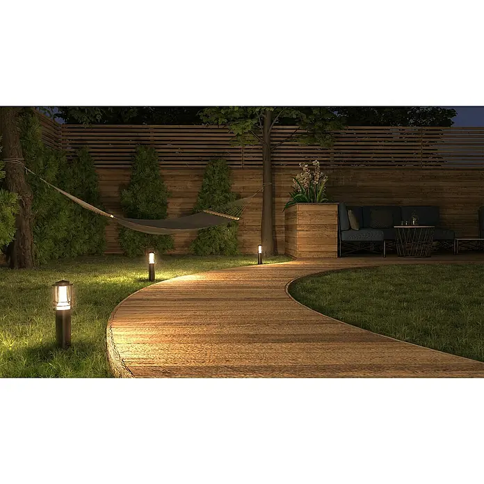 Müller-Licht Tint Außensockelleuchte Petunia - 14 W, Farbe Gehäuse: Schwarz, RGBW, Mit Leuchtmittel - Einladende Gartenansicht bei Nacht mit Holzterrasse, gemütlicher Sitzecke und dekorativer Wegbeleuchtung für eine stimmungsvolle Atmosphäre.