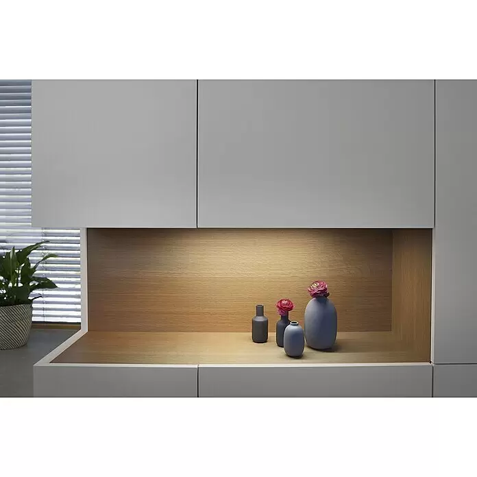 Ledvance LED-Unterbauleuchte Cabinet Sensor - 30 x 10 x 0,8 cm, 5 W, Warmweiß, Gesamtstückzahl: 1 Stk. - Moderne hellgraue Wandregal mit beleuchteter Holznische, die dekorative mattgrau-blaue Vasen mit rosa Blumen und eine grüne Pflanze zeigt.
