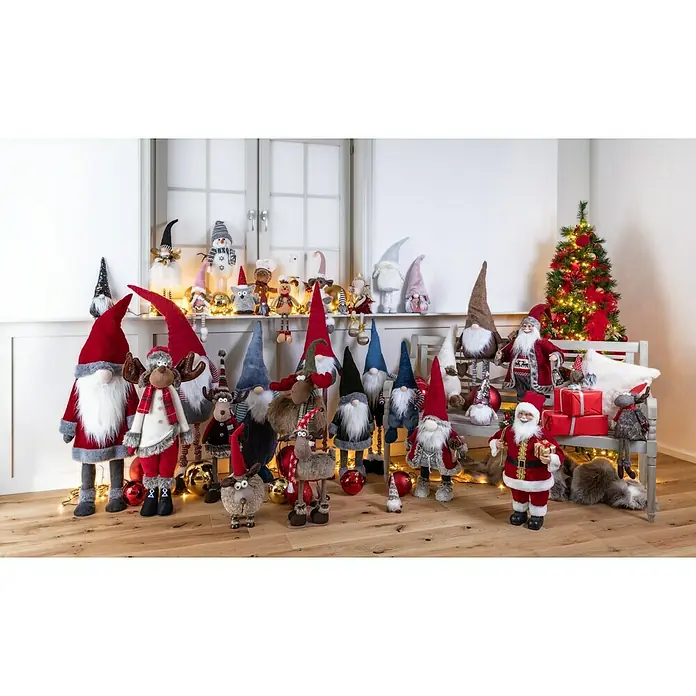 Dekofigur wackelnder Wichtel mit Jutebeutel - L x B x H: 24 x 19 x 78 cm, Textil - Vielfältige Auswahl an Weihnachtsdekoration mit festlichen Zwergen, Rentieren und Weihnachtsmännern vor einem dekorierten Baum und Geschenken.