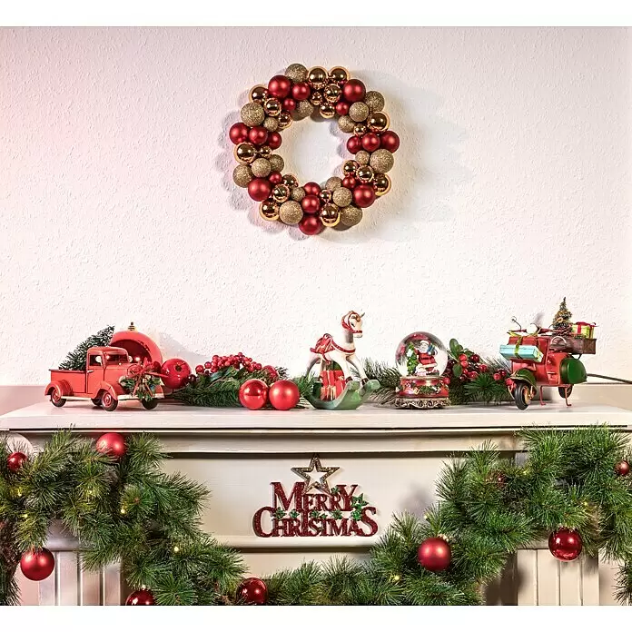 Schneekugel mit Spieluhr - Kunststoff, Weihnachtsmann - Eine festliche Weihnachtsdekoration mit einem Kranz aus roten und goldenen Kugeln, einer beleuchteten Girlande und Figuren auf einem Kaminsims.