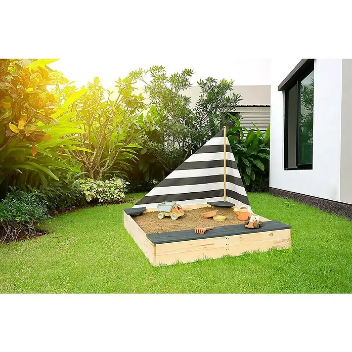 Sun Sandkasten Little Captain - 135 x 125 x 110 cm, Holz - Ein Sandkasten in Form eines Segelbootes mit Spielzeug auf einem grünen Rasen im Garten.