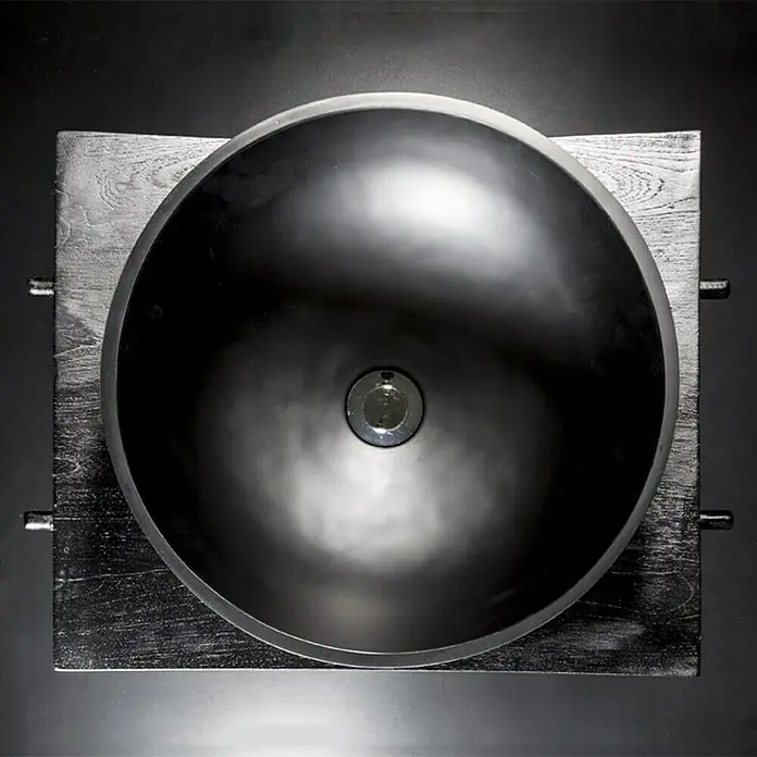 Cipì Lavabo redondo Pop - Diámetro: 38 cm, Negro - Vista superior de un elegante lavabo con una pila redonda y oscura y un tapón de desagüe metálico, montado sobre una elegante superficie de madera.