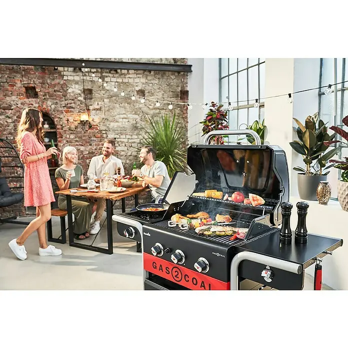 Char-Broil Hybrid-Grill Gas2Coal 2.0 330Grillfläche (B x T): 61,5 x 44,1 cm, 10,1 kW, Anzahl Brenner: 3 - Ein Char-Broil Gas2Coal Hybridgrill in Aktion mit Gästen im Hintergrund, ideal für Grillabende im Freien.