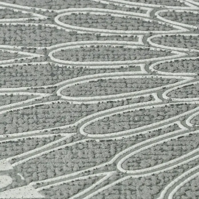 Rasch Tapetenwechsel Vliestapete - Dunkelgrau, Grafisch, 10,05 x 0,53 m - Nahaufnahme einer strukturierten, grauen Fußmatte mit einem eleganten, wiederholenden Muster aus ovalen Formen und Linien, ideal für den Eingangsbereich.