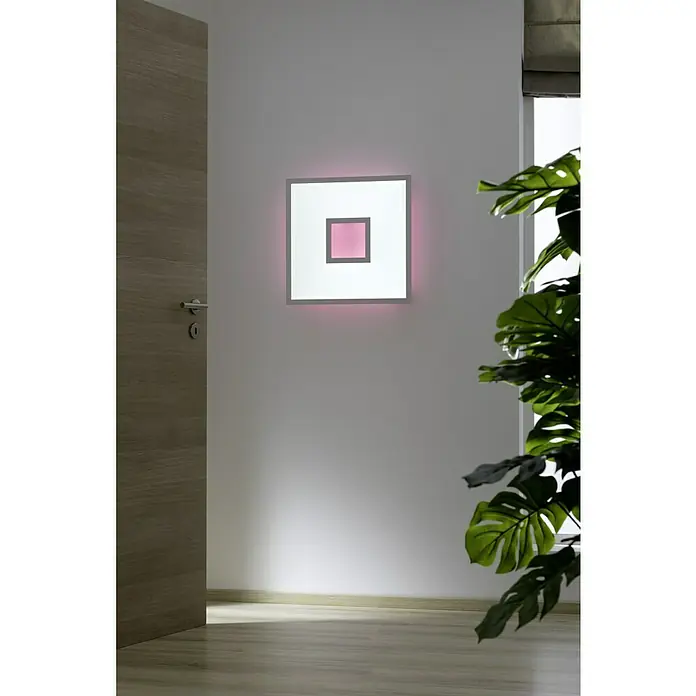 LED-Deckenleuchte Ellia - 24 W, L x B x H: 45 x 45 x 5 cm, Weiß, RGB - Nahaufnahme einer quadratischen Wandleuchte mit grauem Rahmen und rosa Mittelpunkt an einer weißen Wand, neben einer Tür und einer Pflanze.