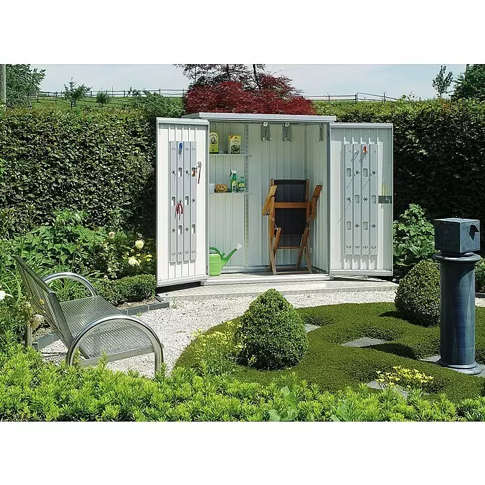 Biohort Geräteschrank 150 - Silber Metallic - Kompakter silberner Geräteschrank mit offenen Türen, der Regale, geordnete Werkzeuge, eine Gießkanne und einen Stuhl in einem Garten zeigt.