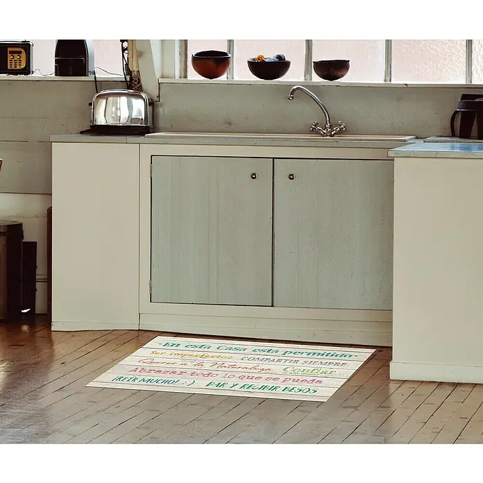 Alfombra de vinilo Croma Tablas - Blanco, 110 x 50 cm - Alfombra acogedora con cita en español en una cocina luminosa, creando un ambiente cálido y acogedor.