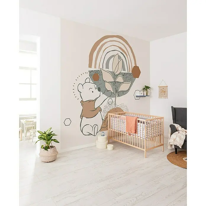 Komar Fototapete Winnie Pooh Grow - B x H: 300 x 280 cm, Vlies - Ein Kinderzimmer mit einer Winnie Puh Wanddekoration, einem Kinderbett und einem grauen Sessel bietet eine gemütliche und verspielte Atmosphäre.