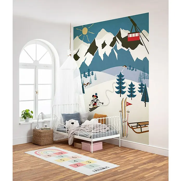 Komar Fototapete Mickey Alpine - B x H: 200 x 280 cm, Vlies - Kinderzimmer mit Bett, Spielteppich und Wandbild. Das Wandbild zeigt eine Winterlandschaft mit Bergen, Skilift und Mickey Mouse beim Skifahren.