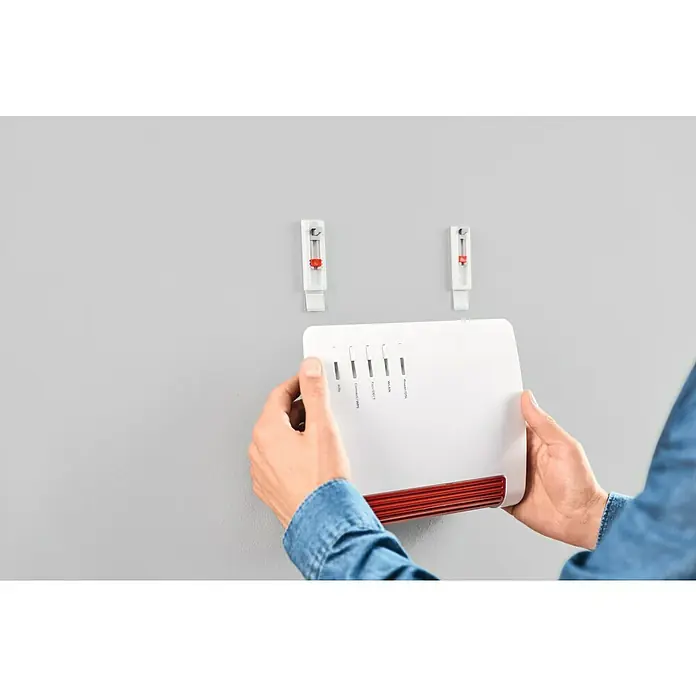 Tesa Powerstrips Klebehaken Adjust Keyhole - Kunststoff, Weiß - Auf dem Bild wird ein FRITZ!Box-Router an einer Wandhalterung montiert, wobei die rote Unterseite des Routers sichtbar ist.