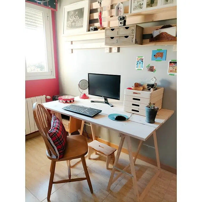Astigarraga Holzklappbock Standard - Tragkraft: 400 kg, Höhe: 74 cm, Kiefer - Schreibtisch mit Computermonitor, Tastatur und diversem Zubehör. Auf dem Tisch steht ein Pflanzgefäß, neben dem Tisch ein Holzstuhl.