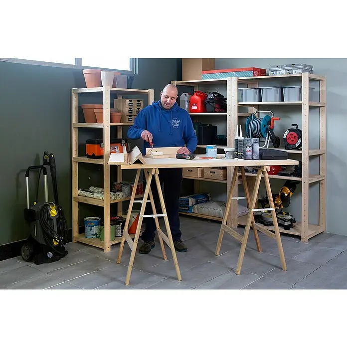 Astigarraga Holzbock - Tragkraft: 600 kg, Höhe: 100 cm, Kiefer, Natur - Heimwerker arbeitet an einem Holztisch in seiner Werkstatt, umgeben von Regalen voller Werkzeuge und Materialien.