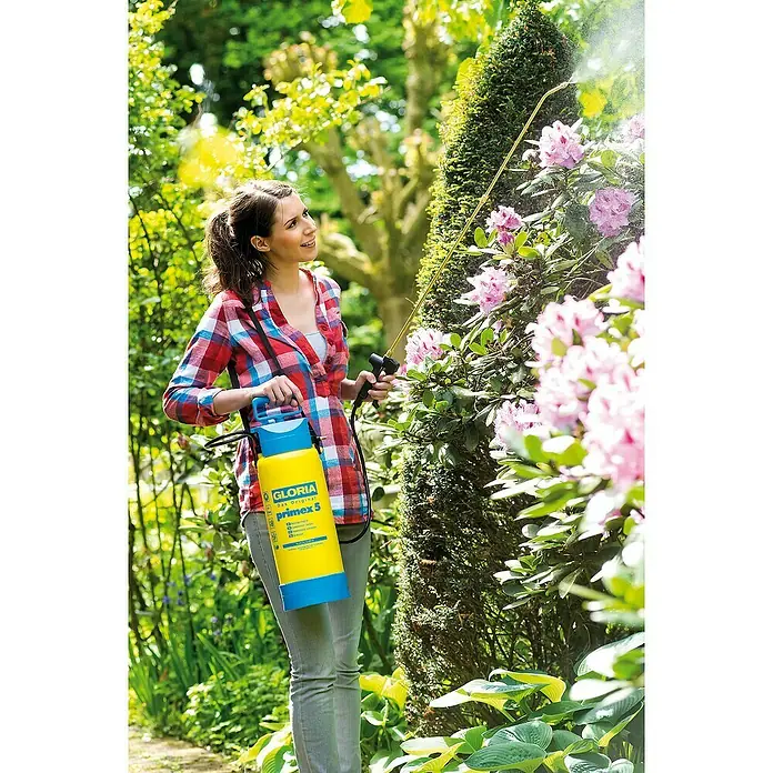 Gloria Drucksprühgerät Primex 5 mit Messing Verlängerungsrohr - 5 l - Eine Frau benutzt einen Gloria Primex 5 Drucksprüher im Garten, um Pflanzen zu pflegen.