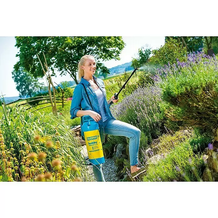 Gloria Sulfatadora Hobby Exclusiv - Presión de funcionamiento: 3 bar, Plástico - Pulverizador GLORIA amarillo y azul usado por una mujer para el cuidado de plantas en un jardín.