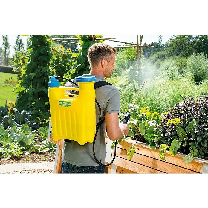 Gloria Kolbenrückensprühgerät Hobby 1200 - Füllmenge: 12 l, Geeignet für: Biologische Spritzmittel - Ein Mann verwendet einen gelben Gloria Rückensprüher im Garten, um Pflanzen zu besprühen. Das Gerät ist zentral im Bild platziert.