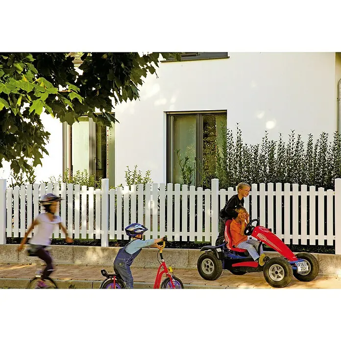 T & J Lightline Vorgartenzaun Hochbogen - 180 x 80 cm, Kunststoff, Gebogen - Ein rotes Tretauto mit Kindern darauf, ein Kind auf einem Fahrrad und ein Kind auf einem Einrad, vor einem weißen Zaun und einem Haus.