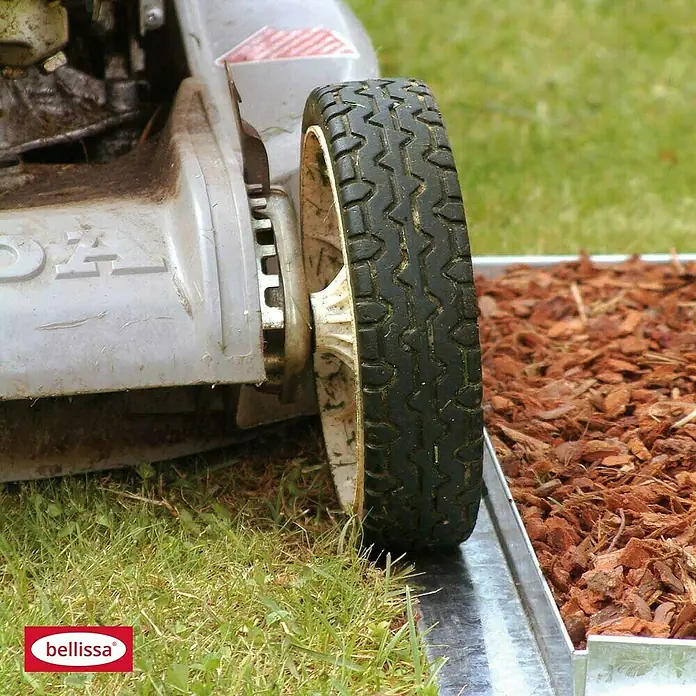 Bellissa Rasenkante Comfort - 118 x 9 cm, Metall, Verzinkt, Mähkante - Nahaufnahme eines Rasenmähers mit Fokus auf der Rasenkante Bellissa, die den Rasen sauber vom Beet trennt.