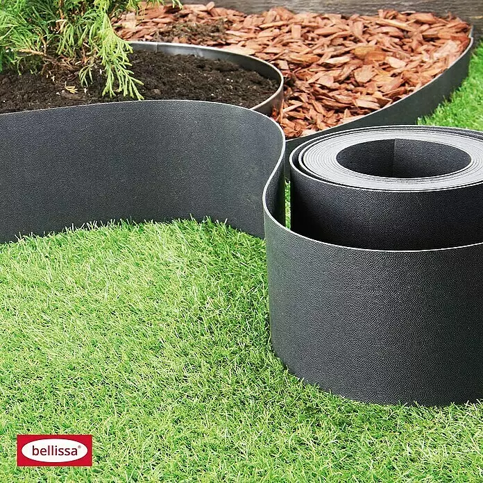 Bellissa Rasenkante - 1.000 x 0,2 x 12 cm, Anthrazit, Polypropylen - Schwarze, texturierte, flexible Gartenumrandung trennt Rasen von Beet; eine Rolle Material liegt im Vordergrund.