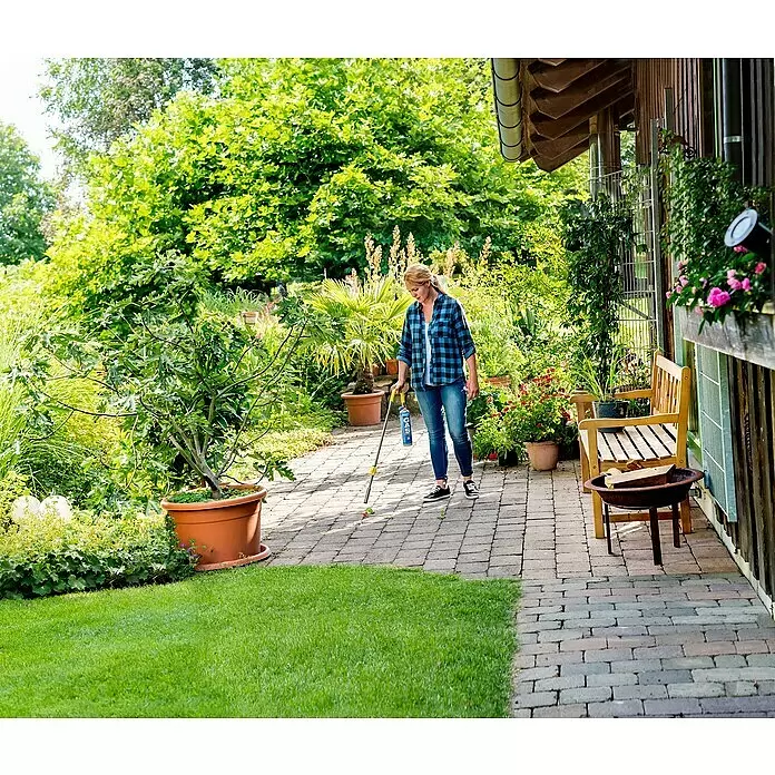 Gloria Unkrautvernichter Thermoflamm bio Classic PLUS - Flammtemperatur: 1.000 °C, Piezo-Zündung - Frau entfernt Unkraut auf einem gepflasterten Gartenweg mit einem Abflammgerät mit gelbem Griff und blauer Gaskartusche.