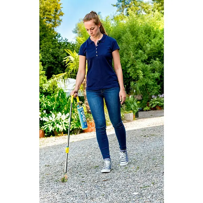 Gloria Unkrautvernichter Thermoflamm bio Classic PLUS - Flammtemperatur: 1.000 °C, Piezo-Zündung - Eine Frau in Jeans und einem Polo-Shirt benutzt einen Gloria Thermoflamm bio Fix Unkrautvernichter mit Gaskartusche im Garten.