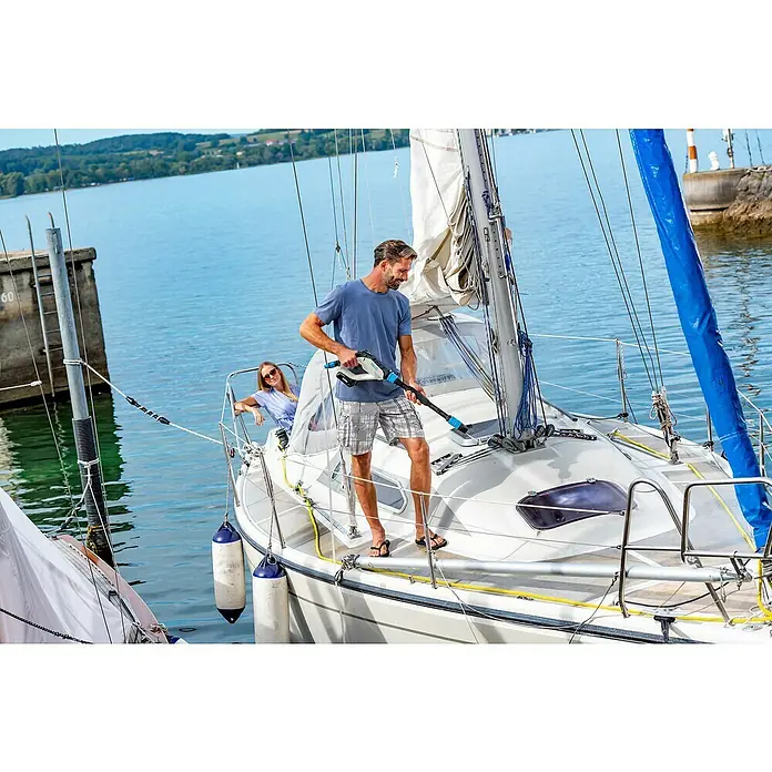 Gloria Power for All 18V Druckreiniger MultiJet - 18 V, Li-Ionen, 1 Akku, Max. Druck: 24,9 bar - Ein Mann benutzt einen tragbaren Reiniger auf einem Segelboot, eine Frau lehnt sich an der Seite an. Ideal für die Bootspflege.