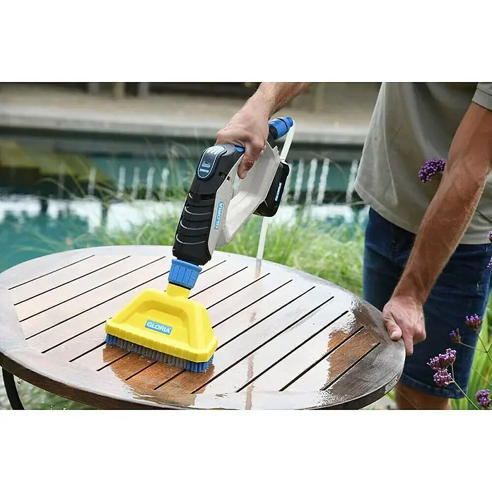 Gloria Power for All 18V Druckreiniger MultiJet - 18 V, Li-Ionen, 1 Akku, Max. Druck: 24,9 bar - Eine Akku-betriebene Reinigungsbürste von Gloria wird verwendet, um einen Holztisch im Freien zu reinigen und zu pflegen.