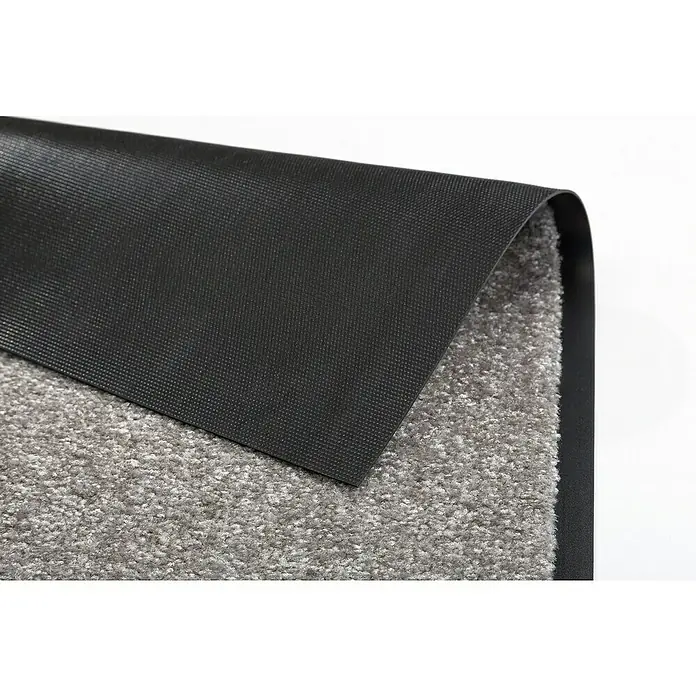 Astra Schmutzfangmatte Proper Tex - Grau, 60 x 180 cm, Material Nutzschicht: 100 % Polyamid - Nahaufnahme einer grauen Fußmatte mit einer schwarzen, rutschfesten Unterseite, die teilweise umgeschlagen ist.