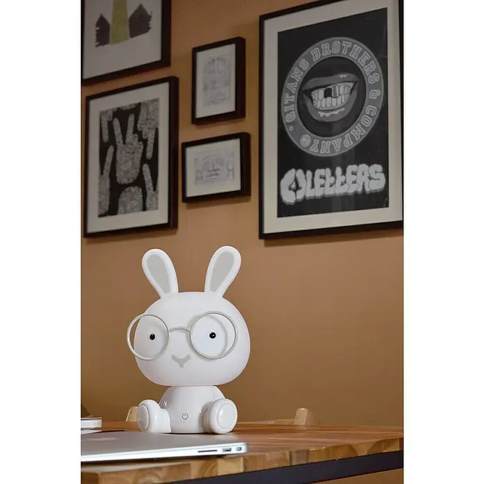 Idp Lampshades Lámpara de sobremesa LED Bunny - 3 W, Ø x Al: 19,5 x 30 cm, Blanco - Lámpara de conejo blanco con gafas sobre una mesa de madera frente a una pared con cuadros. Perfecto como luz nocturna u objeto decorativo.