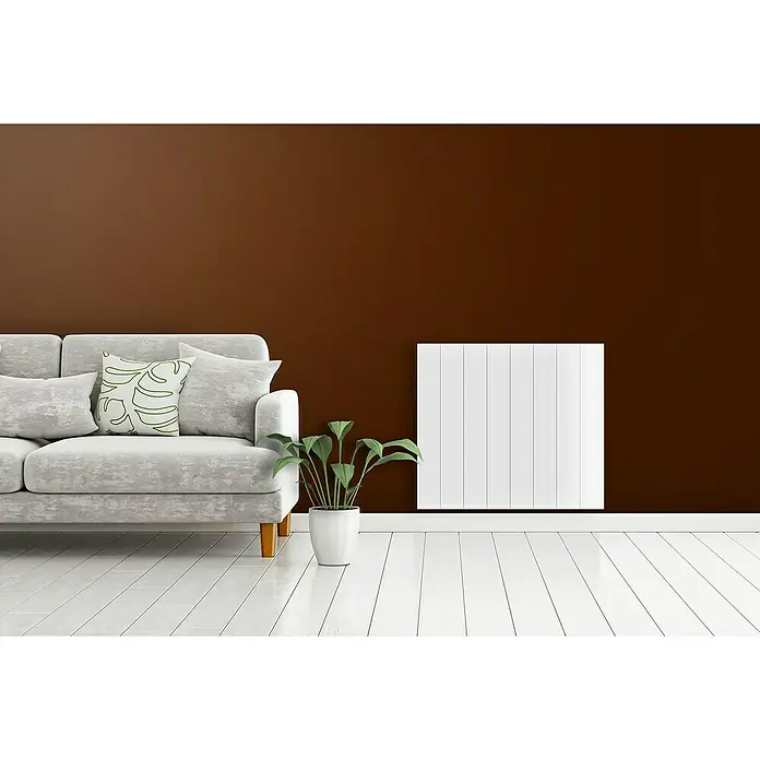 HJM Emisor térmico Ava - 500 W, Blanco, 7,5 x 33,5 x 50 cm, Seco - Vista de salón con radiador blanco en la pared, sofá gris y planta de interior.